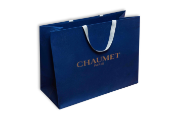 Sac en papier bleu avec inscription dorée et poignées blanches
