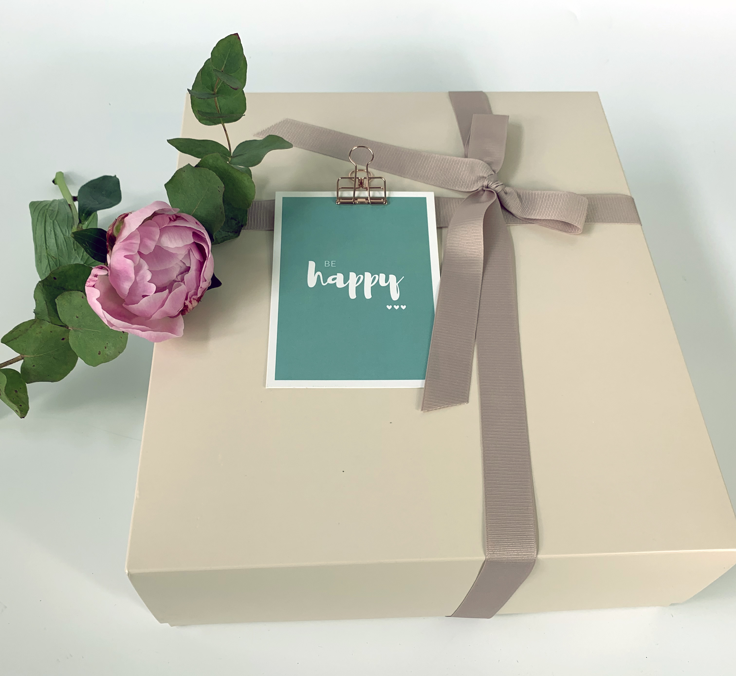 Boîte cadeau beige avec un nœud et une décoration florale