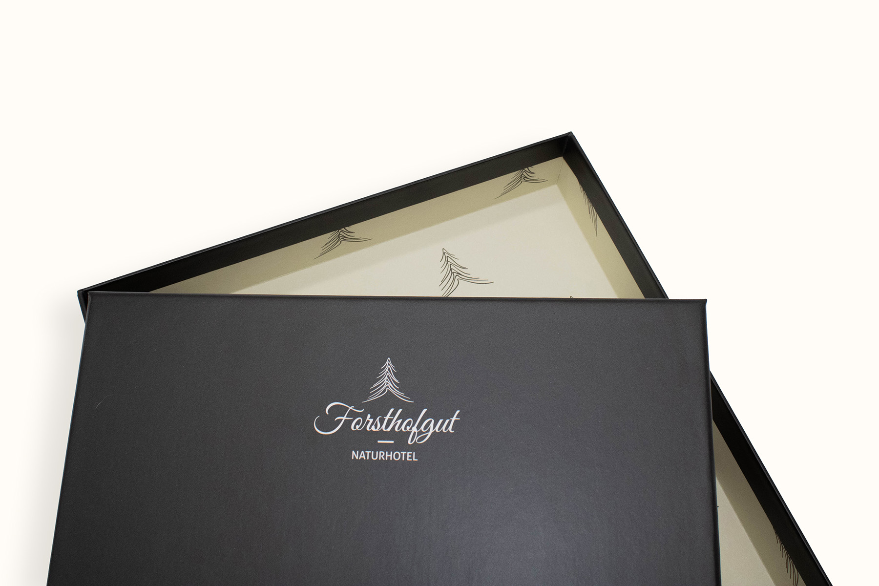 Boîte cadeau noire avec le logo de l’hôtel nature Forsthofgut et couvercle ouvert