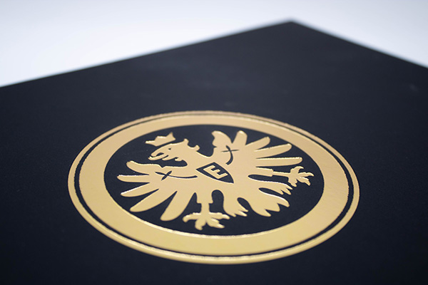 Gros plan d'une boîte à rabat noire avec le logo doré à l'aigle d'Eintracht Francfort