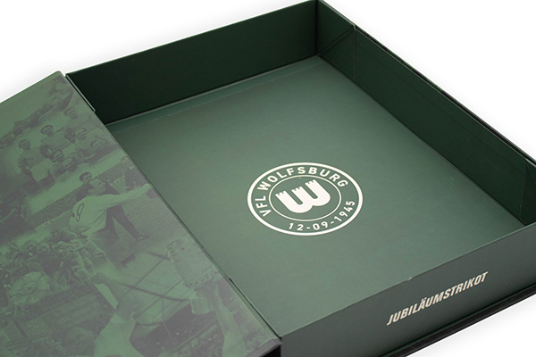 Boîte à maillot verte ouverte avec logo du VfL Wolfsburg et inscription « Jubiläumstrikot »